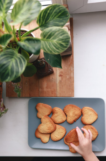 小男孩拿着桌上的心形饼干。情人节、母亲节、妇女节、婚礼或生日平铺概念。前视图。图片下载
