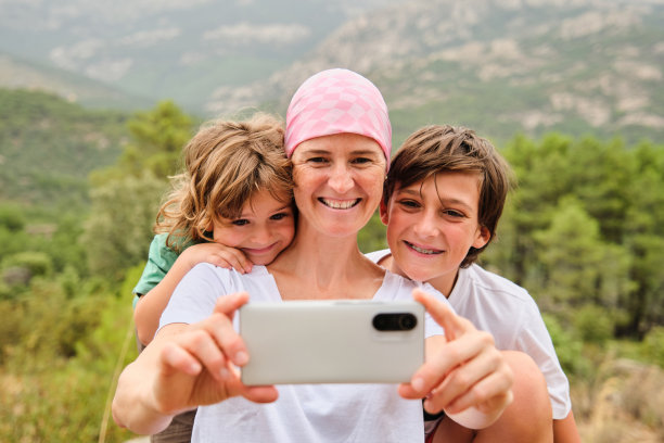 一名女子戴着粉色头巾，用智能手机与家人自拍。图片下载