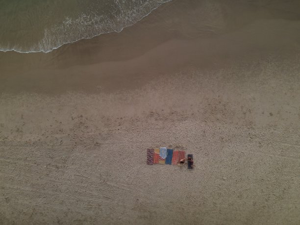 无人机拍摄的海边与海岸毯子和人们放松图片下载