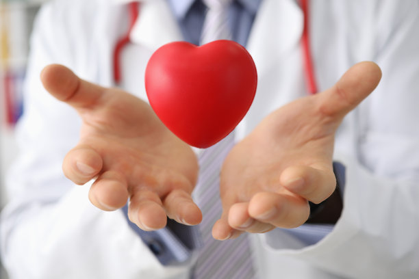 心脏病专家医生的双手将心脏举在空中图片下载