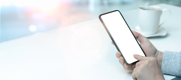 模型的手机。傍晚，坐在咖啡厅的餐桌旁，女人的手指按在手机的白色屏幕上。在咖啡店使用智能手机的女人的手。宽横幅图片下载