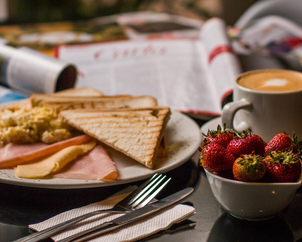 早餐桌上有吐司、炒鸡蛋、火腿、奶酪、草莓和咖啡图片下载
