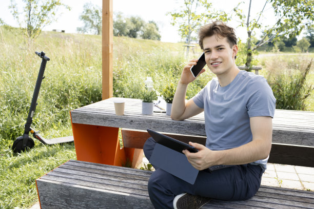 年轻人在公园里工作或学习，坐在木桌旁图片下载