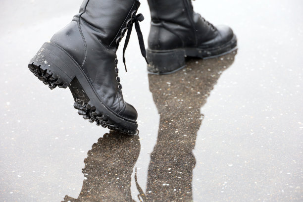 女性的腿在黑色皮靴与反映在水坑上的街道图片下载