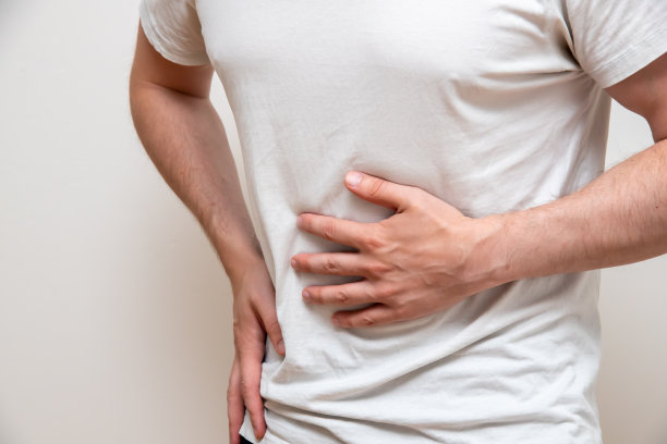 穿着白衬衫的男人因为疼痛而捂着肚子。图片下载