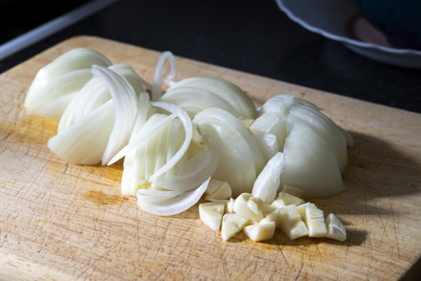 真正的厨房里的木制食物砧板，新鲜切好的洋葱和大蒜来烹饪。图片下载