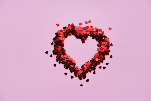 情人节背景。粉红色背景上闪亮的红色小装饰心。平铺，放置文字。图片下载