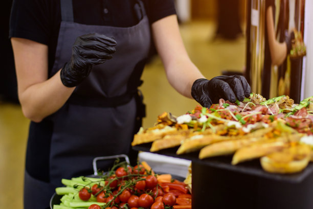 戴着黑色手套的手端三明治。餐饮图片下载