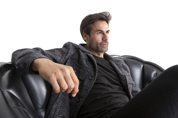 英俊的中年西班牙短粗胡须男子坐在皮革沙发上。图片下载