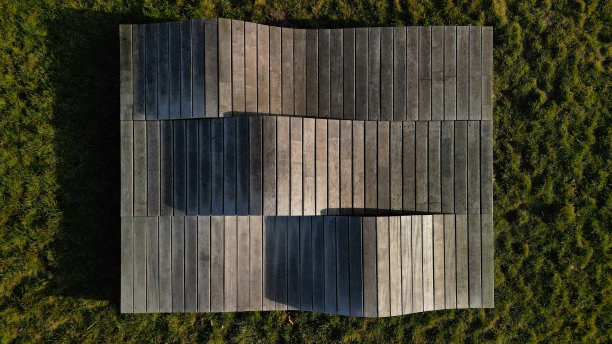 由木板和木板制成的三波甲板椅。景观公园中的大型座椅元素。老人家具，鸟瞰，绿地，三部分，无人机视角，海滩图片下载