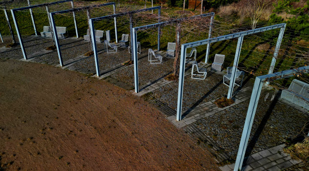 从金属结构到攀爬植物和藤蔓，是一个由粗糙的石头铺装的立方体组成的露台。金属灰色家具，长凳，椅子，咖啡桌，篮子。多年生公园图片下载