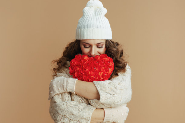 潮流女人在米色毛衣，手套和帽子反对米色图片下载