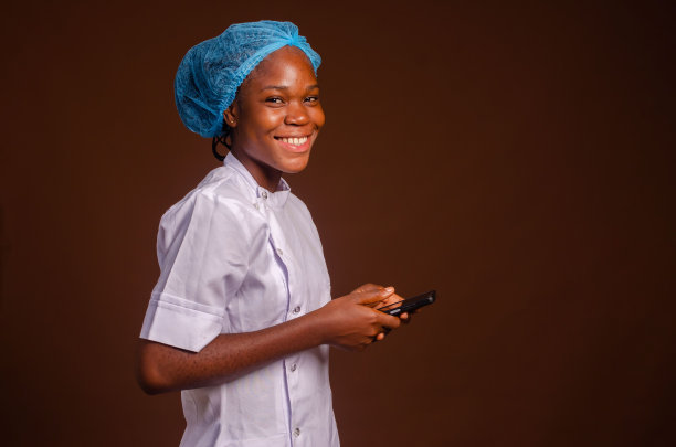 美丽的肖像，一个快乐的护士与电话在她的手在一个棕色的背景图片下载