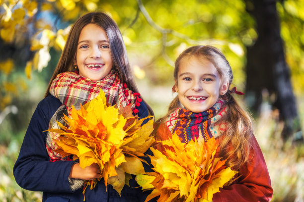 在一个阳光明媚的秋日，两个可爱的8岁女孩在公园里一起摆姿势。图片下载