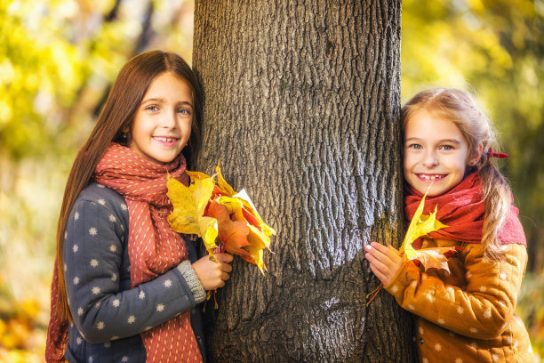 在一个阳光明媚的秋日，两个可爱的8岁女孩在公园里一起摆姿势。图片下载