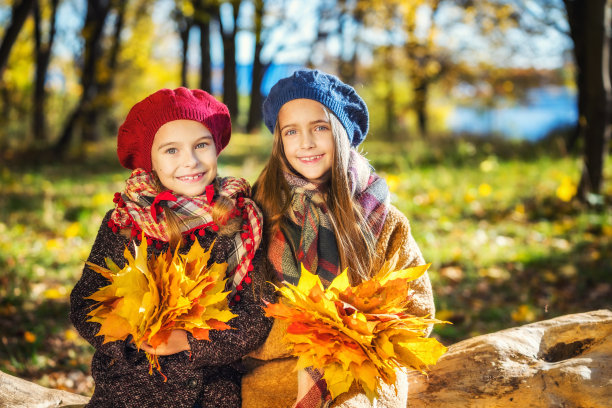 在一个阳光明媚的秋日，两个可爱的8岁女孩在公园里一起摆姿势。图片下载