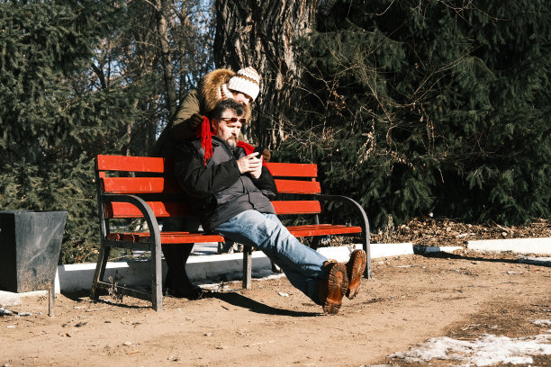 在冬天的公园里，女人正在取男人脖子上的围巾图片下载