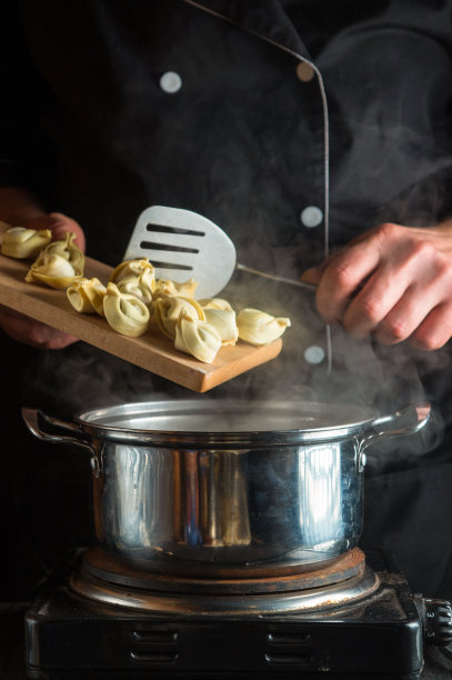 厨师在餐厅厨房用平底锅煮饺子。厨师工作时的手特写图片下载