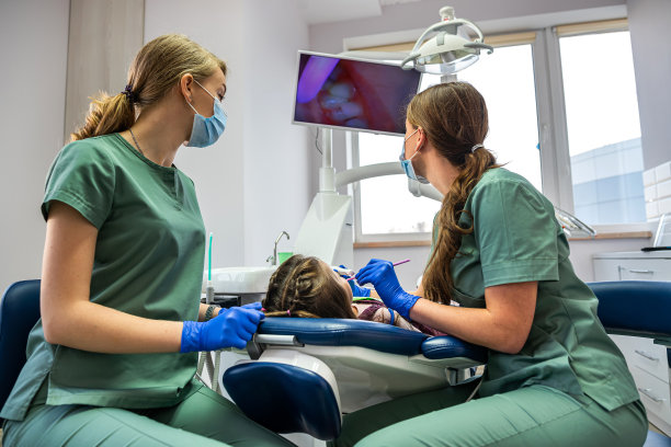 牙医用照相机检查孩子的牙齿，并把照片显示在屏幕上。图片下载