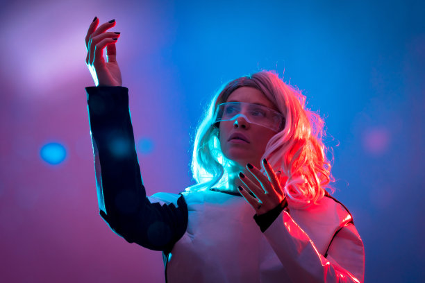 美丽的女人透过未来的眼镜，黑暗的背景，未来和虚拟现实的概念图片下载