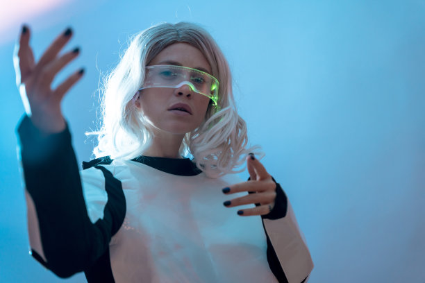 女人戴着明亮的未来眼镜，蓝色背景，在虚拟现实中移动控制器图片下载