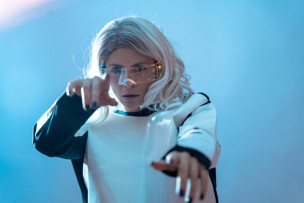 女人透过明亮的未来眼镜，蓝色背景，享受虚拟现实图片下载