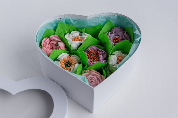 在白色孤立的背景谎言礼品盒的心形与甜蜜的棉花糖花。图片下载