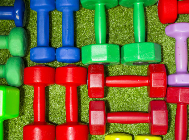 绿色草地背景上的彩色哑铃图片下载