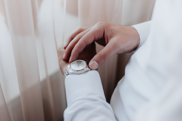 窗边穿蓝色夹克的新郎看了看手表。图片下载