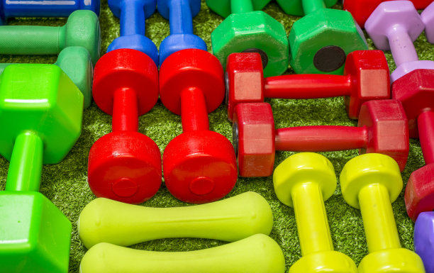 绿色草地背景上的彩色哑铃图片下载