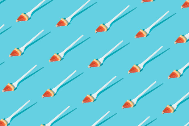 用叉子在蓝色背景上切成薄片的葡萄柚做成的图案。创意健康零食水果概念。图片下载