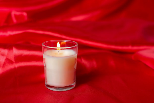 豪华舒适的蜡烛在罐子与红色织物背景，干芦苇波西米亚风格。燃烧香薰蜡烛，手工蜡烛，高质量的照片，情人节浪漫的概念图片下载