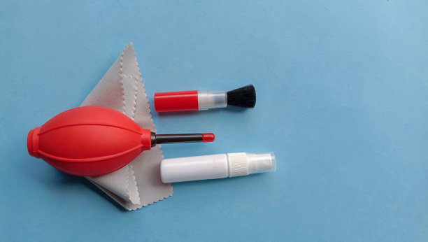 照片的相机清洁用品，如鼓风机，刷子，超纤维布，水喷雾在蓝色的背景图片下载