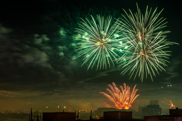 午夜时分，五彩缤纷的烟花在城市上空绽放。绿色的烟花爆炸和红色的喷泉在夜空中庆祝节日。节日烟火和鞭炮。夜景。图片下载