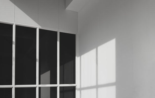 黑色有色玻璃表面的阳光和阴影与办公楼的白色水泥墙图片下载