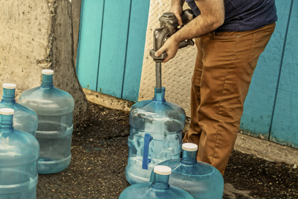 在美国阿拉斯加州，一名年轻男子在没有自来水的干燥船舱里装满了5加仑的罐子图片下载