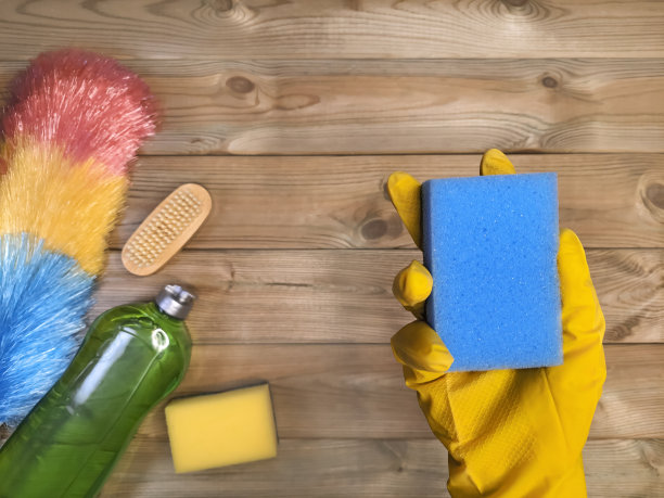 前景中戴橡胶手套的女性手握海绵。木质表面清洁项目。房屋清洁概念。Flatlay。Copyspace图片下载
