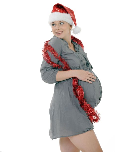 年轻的孕妇戴着圣诞老人的帽子和金属丝，在白色背景上触摸她的肚子图片下载