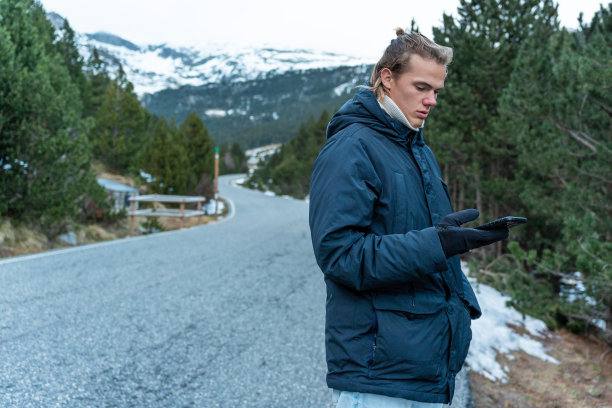 一个男孩在山路中间玩手机。图片下载