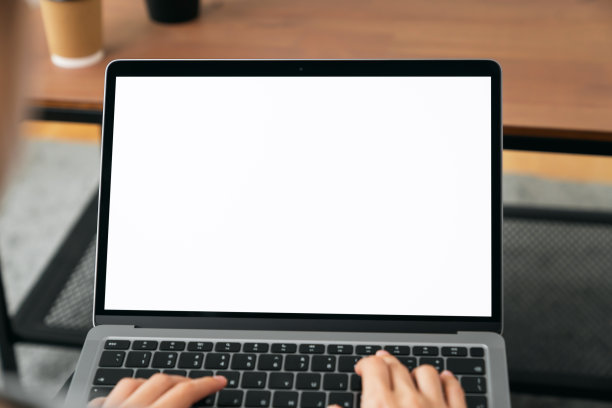 女手使用笔记本电脑和键盘上打字与样机的空白屏幕在木桌上。图片下载