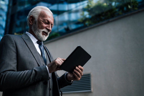 自信的企业家分析数字平板电脑与商业办公楼的想法图片下载