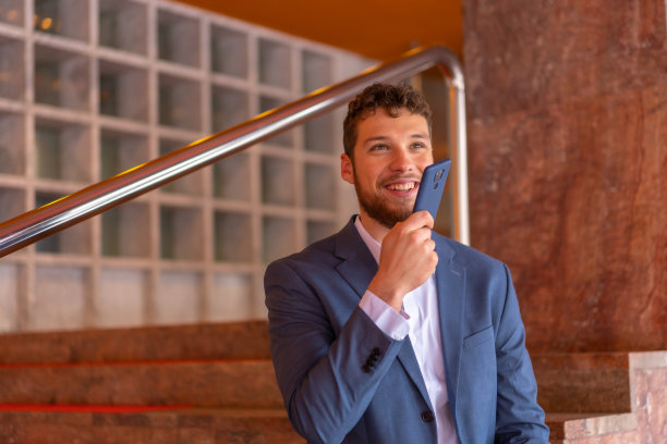 商人或金融人员在酒店门口微笑着拿着电话远程办公图片下载