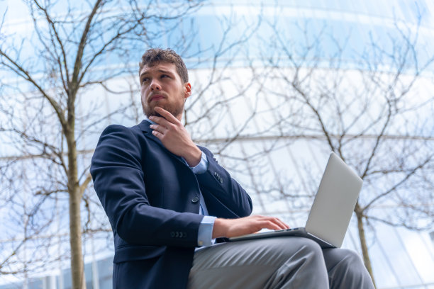 年轻的商人或金融人士在进入会场前思考，玻璃大厦图片下载