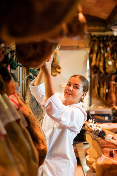在杂货店柜台后面工作的女售货员，检查火腿的质量图片下载