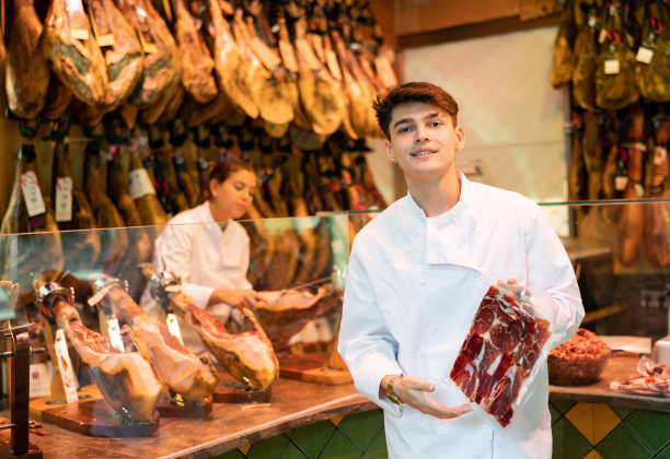 身穿白色制服的年轻肉店卖家提供真空包装的切片图片下载