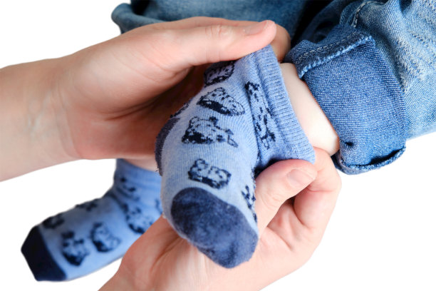 一位穿着蓝袜子的母亲抱着一个脚上的男婴，他被孤立在白色背景上。妈妈给有腿的孩子穿上衣服。孩子九个月大图片下载