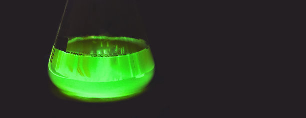 在黑暗中发光的实验室烧瓶。炼金术魔法药水。绿色有毒毒药。装有绿色荧光药物的玻璃烧杯图片下载