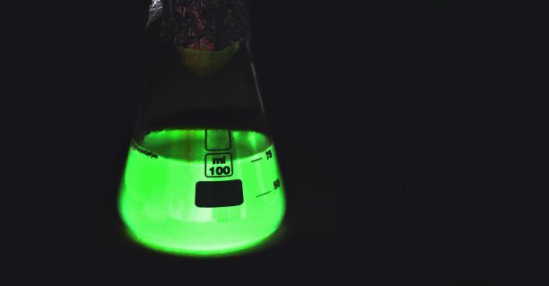 在黑暗中发光的实验室烧瓶。炼金术魔法药水。绿色有毒毒药。装有绿色荧光药物的玻璃烧杯图片下载