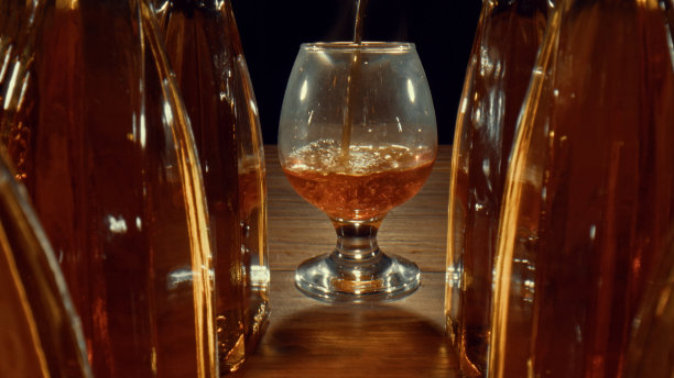 饮料正倒在干邑和威士忌旁边的玻璃杯里图片下载
