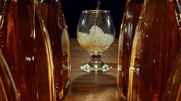 一瓶瓶威士忌和一杯冰正被盛满的饮料图片下载
